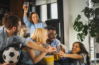 Heyecanlı, çok ırklı bir grup genç, evlerinde TV 'de futbol maçı izliyor.