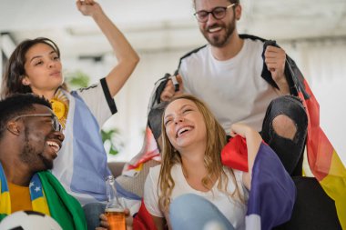 Heyecanlı, çok ırklı bir grup genç, evlerinde TV 'de futbol maçı izliyor.