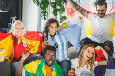 Heyecanlı, çok ırklı bir grup genç, evlerinde TV 'de futbol maçı izliyor.