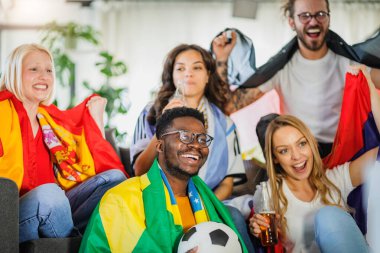 Heyecanlı, çok ırklı bir grup genç, evlerinde TV 'de futbol maçı izliyor.