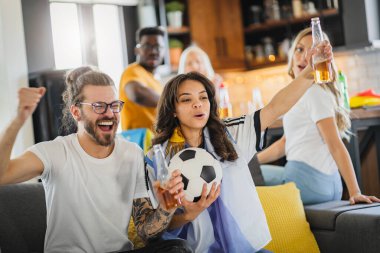 Heyecanlı, çok ırklı bir grup genç, evlerinde TV 'de futbol maçı izliyor.