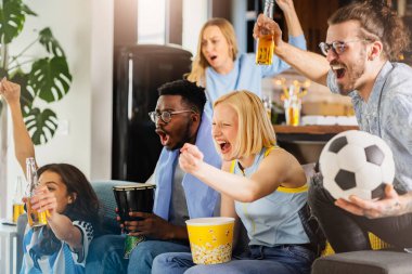 Heyecanlı, çok ırklı bir grup genç, evlerinde TV 'de futbol maçı izliyor.
