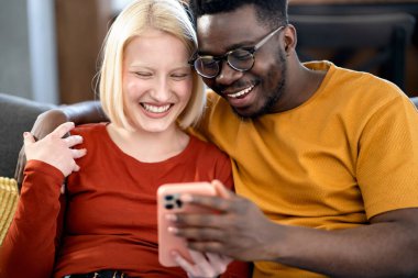 İçerideki akıllı telefondan bir şey arayan çok ırklı mutlu bir çift.