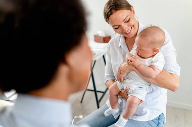 Anne ve bebek Afrikalı Amerikalı doktoru ziyaret ediyor. 