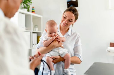 Anne ve bebek Afrikalı Amerikalı doktoru ziyaret ediyor. 