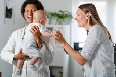 Anne ve bebek Afrikalı Amerikalı doktoru ziyaret ediyor. 