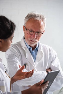 Erkek ve kadın doktorlar taşınabilir bir tablet bilgisayara bakıyorlar.