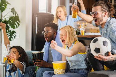 Heyecanlı, çok ırklı bir grup genç, evlerinde TV 'de futbol maçı izliyor.