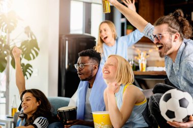 Heyecanlı, çok ırklı bir grup genç, evlerinde TV 'de futbol maçı izliyor.