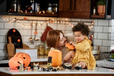 Anne ve tatlı küçük kız mutfakta Jack-o-Lantern ile eğleniyorlar. Cadılar Bayramı