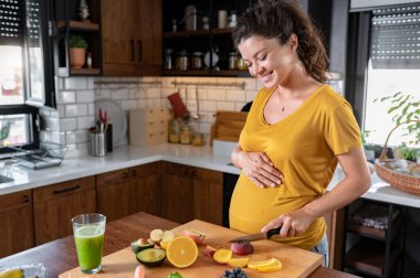Mutfakta yemek yapan hamile bir kadın, sağlıklı beslenme konsepti.