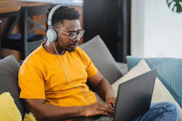 stock image African-American young student at home, listening to online classes, or a webinar over a laptop computer