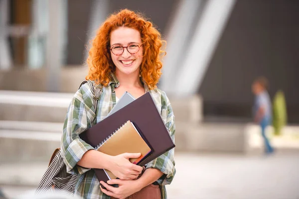 大学の建物の前に美しい笑顔の赤い髪の学生の女の子の肖像 — ストック写真