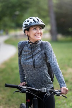Parkta bisiklet süren genç bir kadın. 