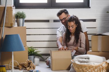 Mutlu çok ırklı çift yeni boş bir daireye taşındılar bavullarını boşaltıp, temizleyip, yeni evlerinin tadını çıkarıyorlar. Yeniden yerleştirme. İçeri giriyoruz..