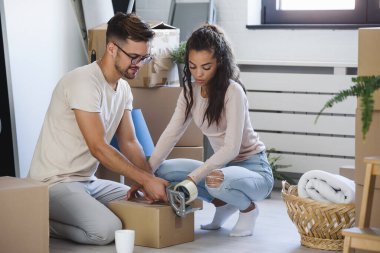 Mutlu çok ırklı çift yeni boş bir daireye taşındılar bavullarını boşaltıp, temizleyip, yeni evlerinin tadını çıkarıyorlar. Yeniden yerleştirme. İçeri giriyoruz..