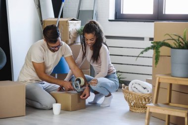 Mutlu çok ırklı çift yeni boş bir daireye taşındılar bavullarını boşaltıp, temizleyip, yeni evlerinin tadını çıkarıyorlar. Yeniden yerleştirme. İçeri giriyoruz..