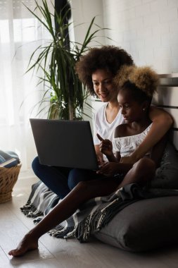 Afro-Amerikan anne ve kızı dizüstü bilgisayar kullanıyor.