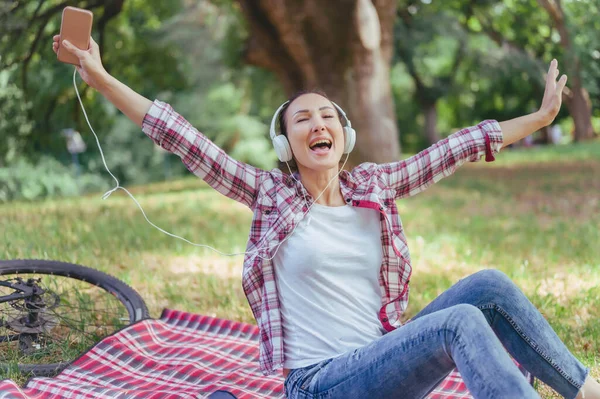 Genç Bir Kadın Parkta Kulaklıkla Müzik Dinliyor — Stok fotoğraf