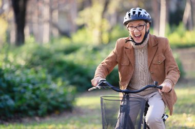 Kamu parkında bisiklet süren neşeli yaşlı kadın. Yaşlılar için etkinlikler