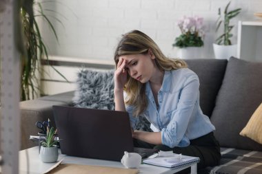 Evde bilgisayar başında çalışan endişeli genç bir kadın aylık giderleri hesaplıyor, ipotek ödemelerini yapıyor, maddi sorunları var.