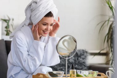 Evde bornoz giyen güzel bir kadının portresi. Günlük cilt bakımını doğal kozmetiklerle yapıyor.