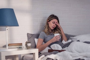 Hasta olduğu için evde. Kadının soğuk algınlığı var. Öksür. Soğuk algınlığına ya da gribe yakalanmış güzel genç bir kadının yakın çekimi. Boğazında Ağrı Olan Sağlıksız Bir Kızın Portresi.