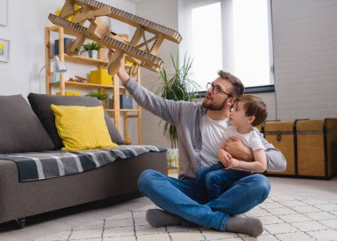 Baba ve küçük çocuk karton uçakla oynuyorlar.
