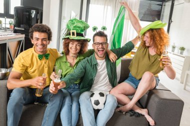 Bir grup arkadaş futbol izleyip bira içiyorlar.