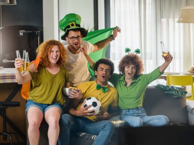 Bir grup arkadaş futbol izleyip bira içiyorlar.