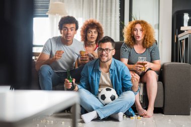 Bir grup arkadaş futbol izleyip bira içiyorlar.