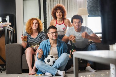 Bir grup arkadaş futbol izleyip bira içiyorlar.