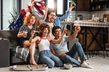 Bir grup arkadaş futbol izleyip bira içiyorlar.