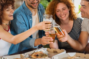 Arkadaşlar pizza yiyor ve bira içiyor.