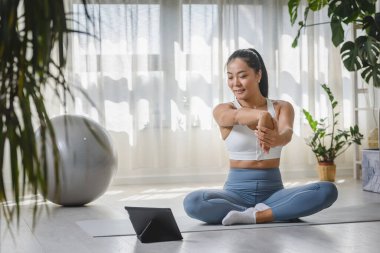 Güzel genç bir kadın oturma odasında yoga egzersizleri yapıyor. 