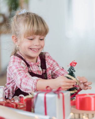 Küçük kız Noel süsleri ve hediyelerle oynuyor.