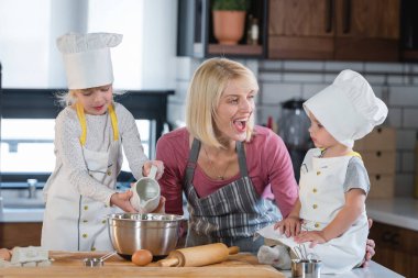 Mutlu anne, kız ve oğlanla yemek yapıyor.