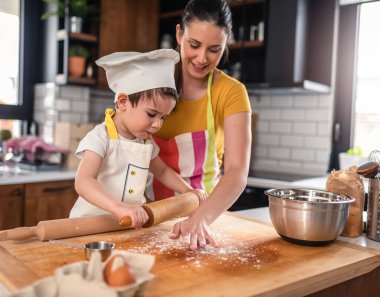 Anne oğluyla yemek yapıyor. Hamurla çalışmak