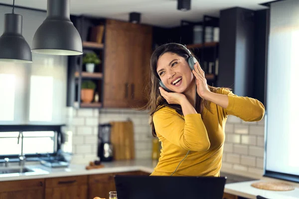 Young smiling woman with headphones working from home, taking break listening music and singing. Positive emotions. Woman with positive attitude.