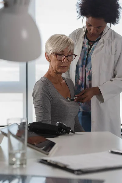 黒人女性医師が事務所に座り 高齢女性患者を診察する 心臓検査 — ストック写真