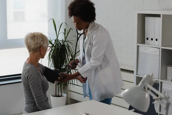 黒人女性医師が事務所に座り 高齢女性患者を診察する 心臓検査 — ストック写真