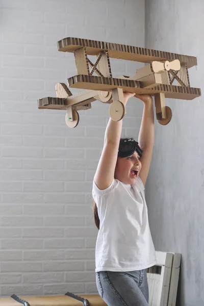Adorable child playing with cardboard plane at home