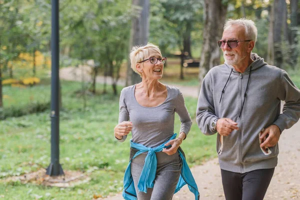 Cheerful, active senior couple jogging in the park. Exercise together to stop aging.