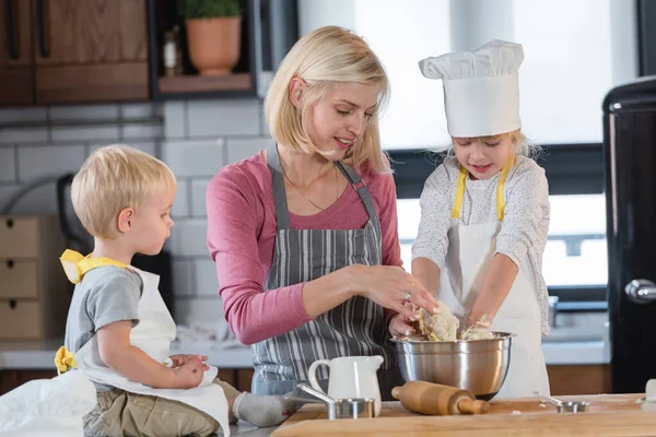 幸せな母は娘と息子と料理をする — ストック写真