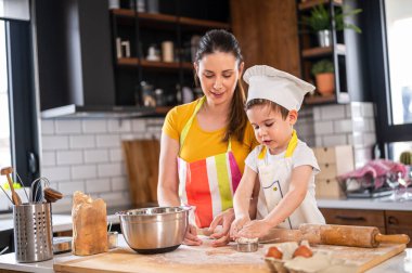 Anne oğluyla yemek yapıyor. Hamurla çalışmak