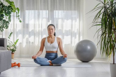 Genç Asyalı kadın evde yoga egzersizi yapıyor. Sağlıklı bir yaşam tarzı ve stres atma için günlük spor programları.