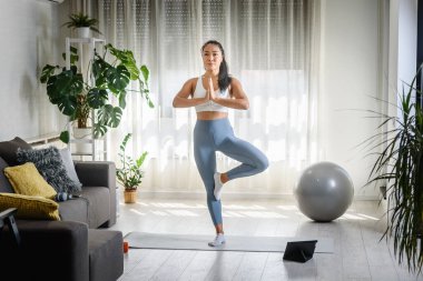 Genç Asyalı kadın evde yoga egzersizi yapıyor. Sağlıklı bir yaşam tarzı ve stres atma için günlük spor programları.