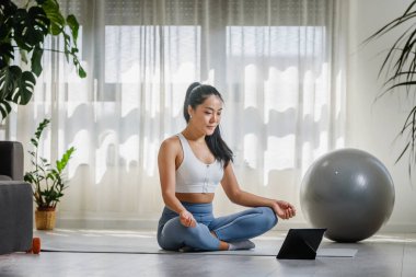 Genç Asyalı kadın evde yoga egzersizi yapıyor. Sağlıklı bir yaşam tarzı ve stres atma için günlük spor programları.