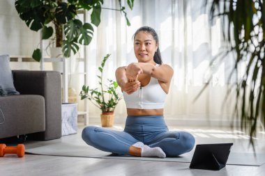Genç Asyalı kadın yoga eğitmeni online yoga sınıfında tablet bilgisayar kullanıyor.