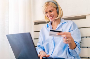 Genç bir kadın internet üzerinden ödeme yapmak için kredi kartını kullanıyor.